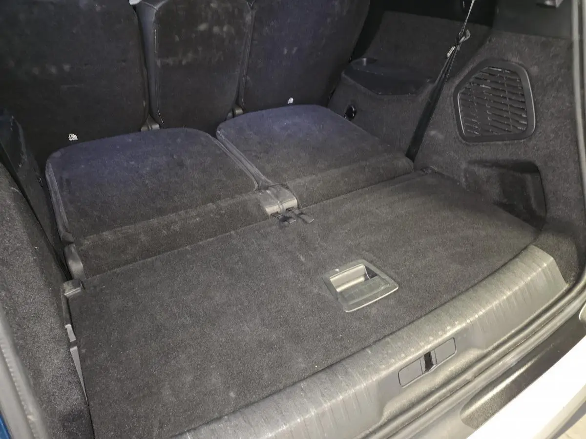 Coffre du Peugeot 5008 2025 avec banquette arrière rabattue, revêtement tissu noir et espace de chargement plat.
