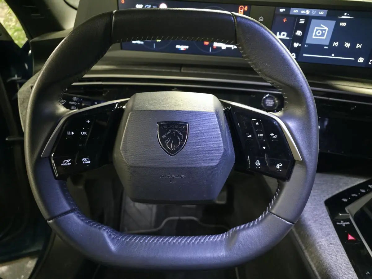 Gros plan sur le volant noir en cuir du Peugeot 5008 2025 avec commandes intégrées et logo central lion.