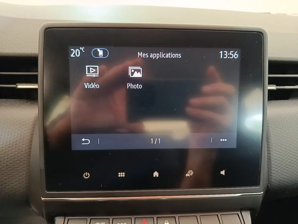 Écran tactile central affichant les applications vidéo et photo dans l'habitacle d'une Renault Clio gris foncé.