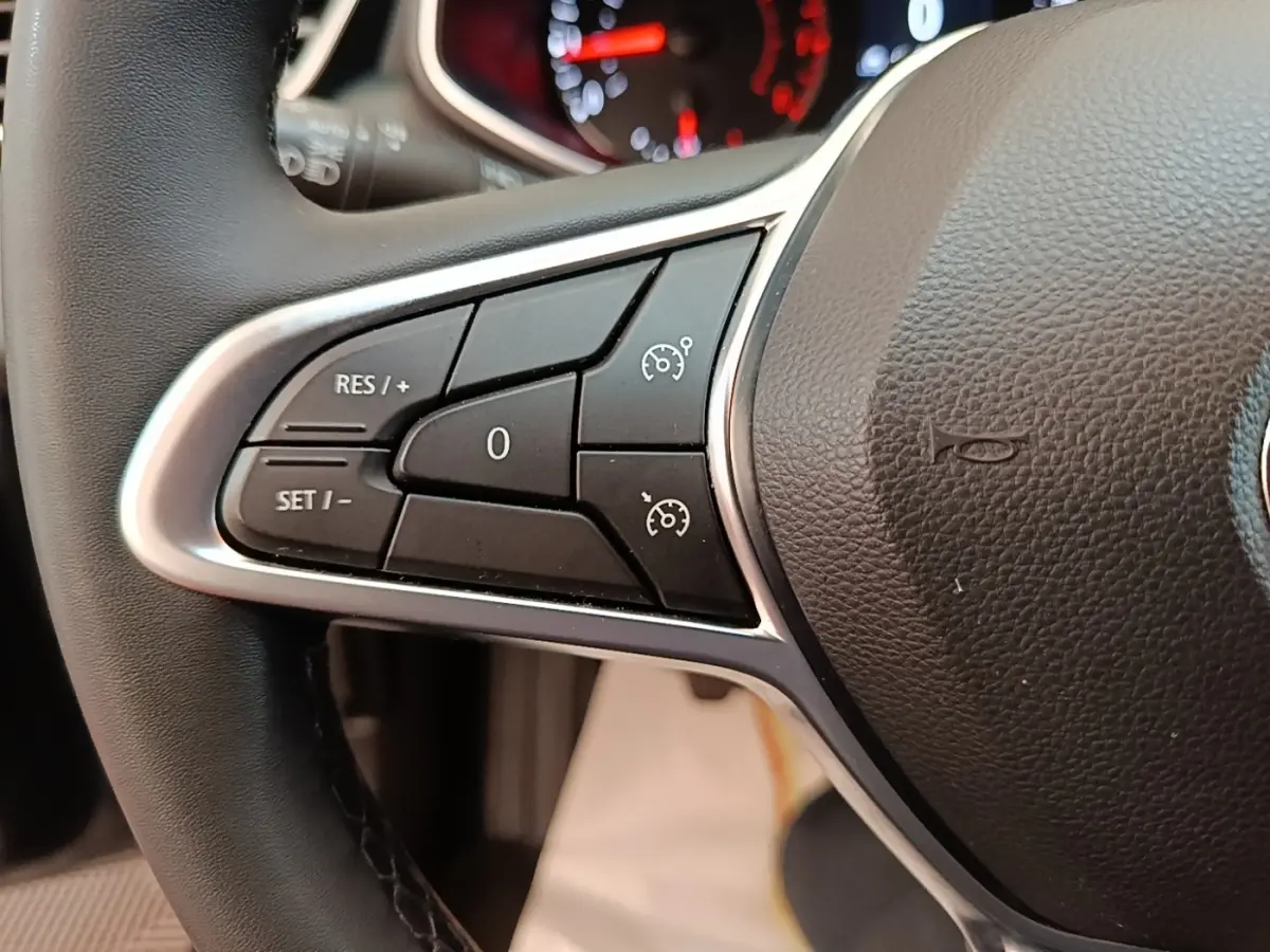 Gros plan sur les commandes du régulateur de vitesse au volant cuir noir de la Renault Clio Business TCe 100.