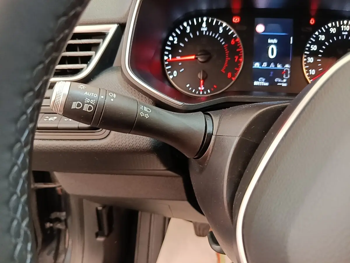 Vue rapprochée du tableau de bord et du commodo des phares d’une Renault Clio Business TCe 100, intérieur noir.