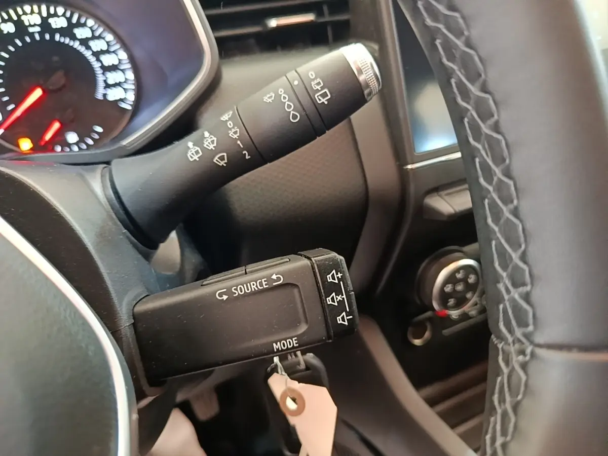 Gros plan sur la commande au volant et le tableau de bord de la Renault Clio Business gris foncé, avec affichage digital partiel.