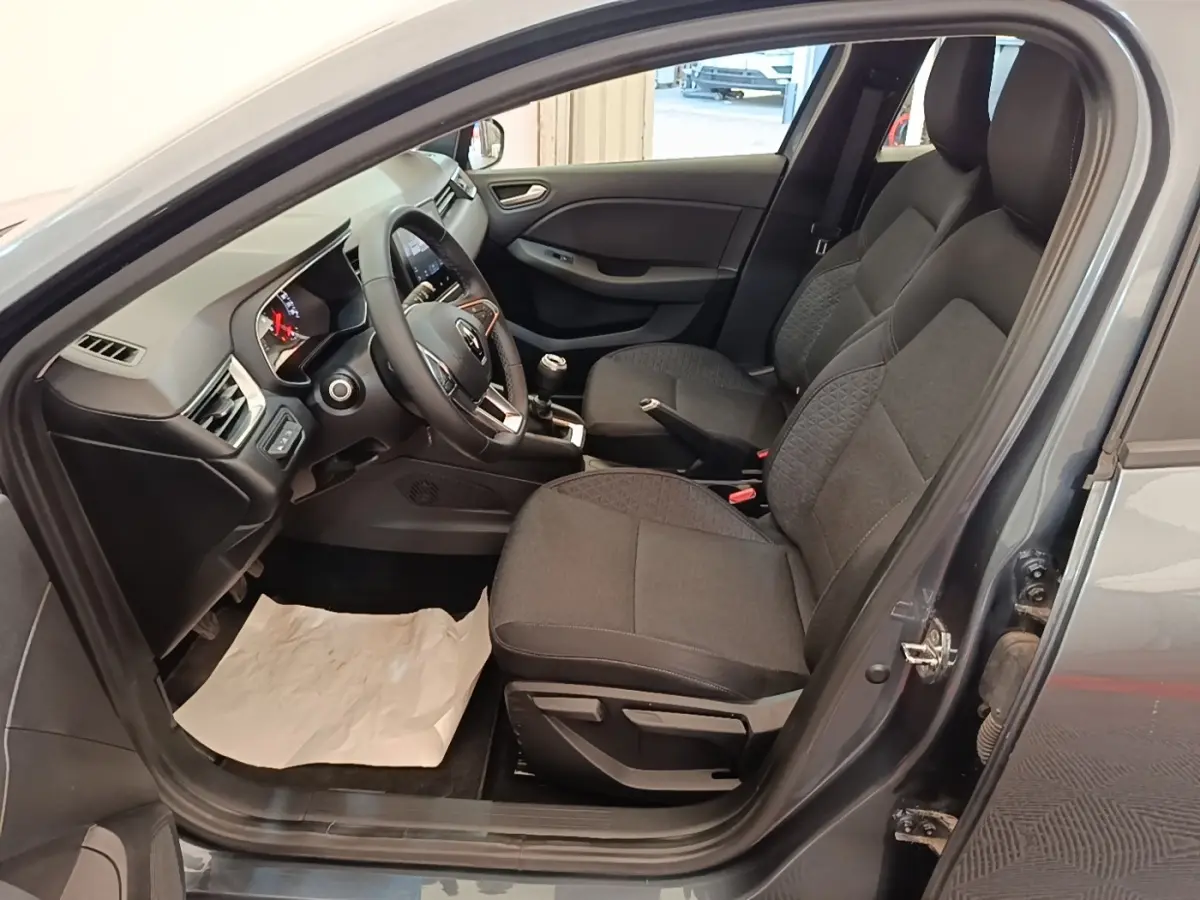 Intérieur côté conducteur d'une Renault Clio Business TCe 100 gris foncé, montrant sièges tissu et tableau de bord avec volant multifonctions.