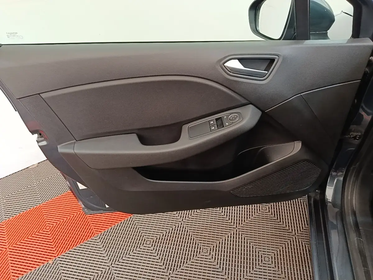 Vue intérieure côté gauche de la porte avant gris foncé de la Renault Clio Business TCe 100 avec commandes de vitres.