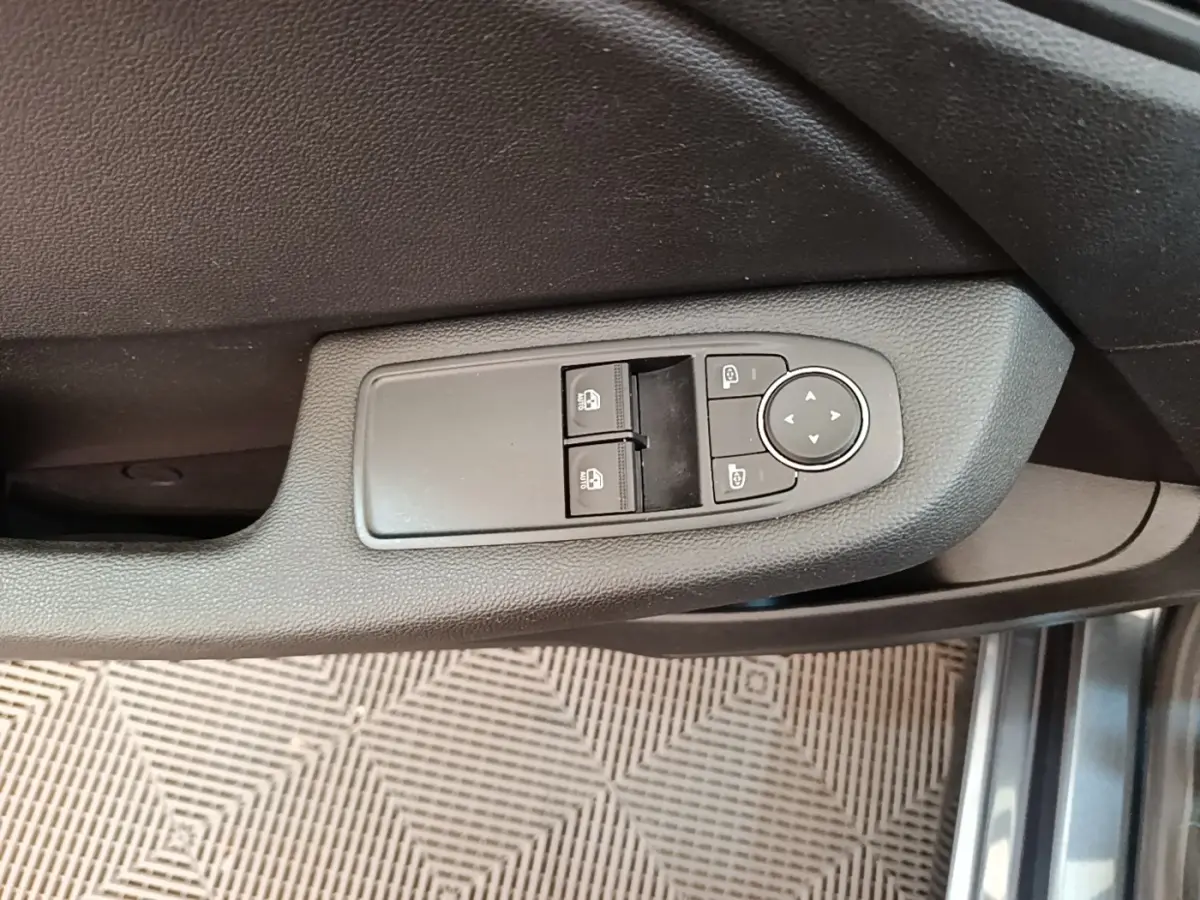 Commande des vitres et rétroviseurs sur la porte côté conducteur d'une Renault Clio Business TCe 100 gris foncé, vue intérieure rapprochée.