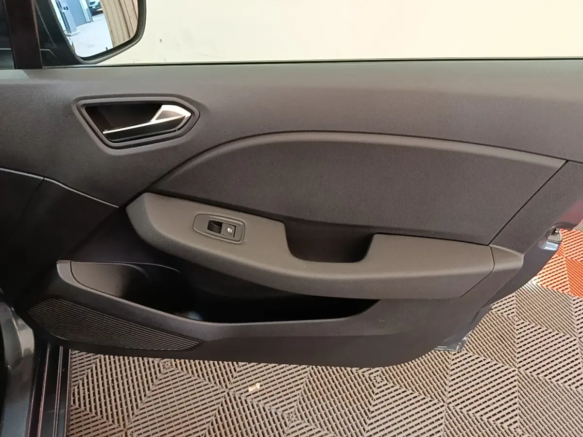 Gros plan sur la porte intérieure côté gauche de la Renault Clio Business TCe 100 gris foncé, avec poignée et commande de vitre.