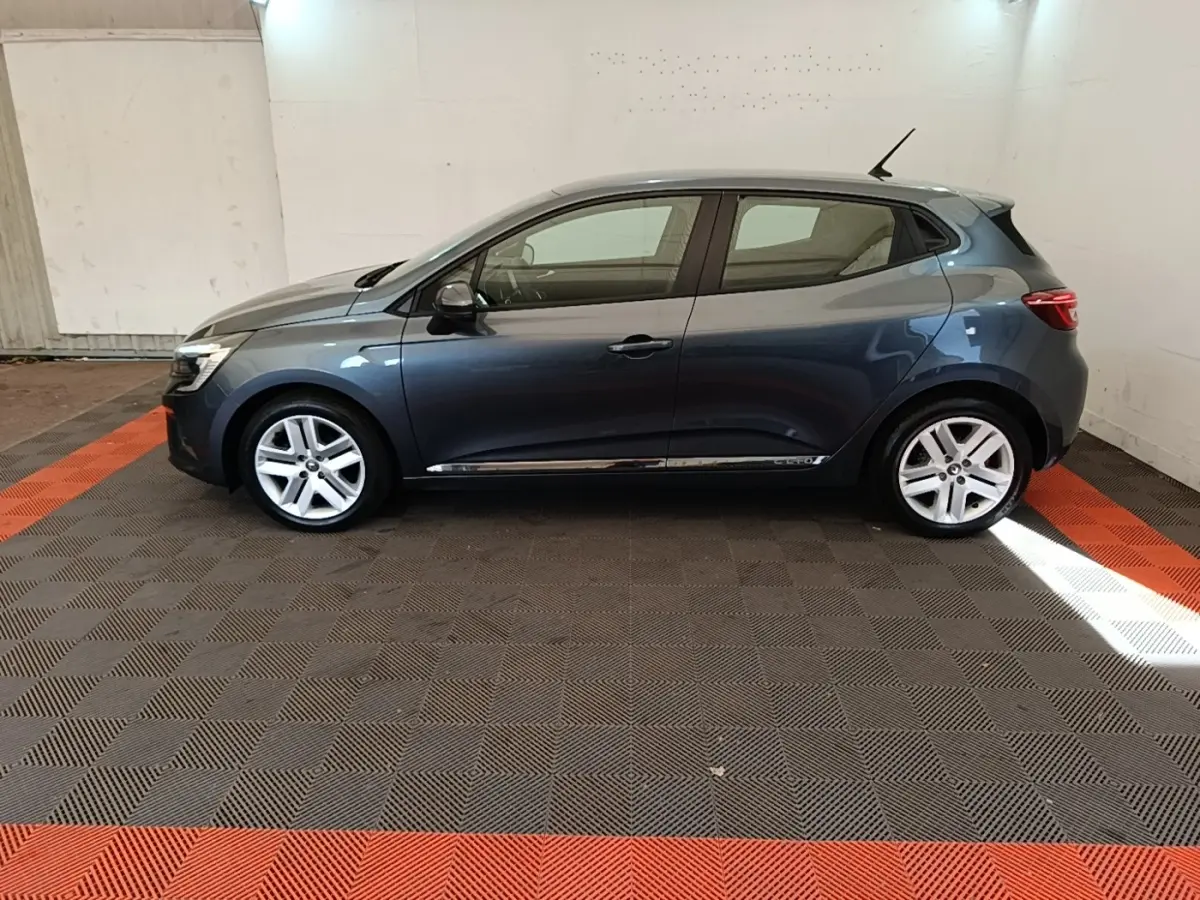 Profil droit d'une Renault Clio Business TCe 100 gris foncé, avec jantes alliage et toit compact dans un garage.