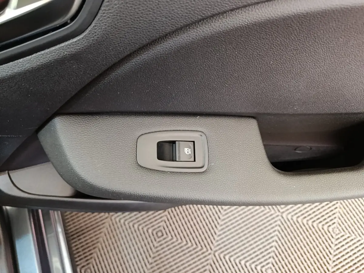 Détail de la commande de verrouillage centralisé sur la porte intérieure d’une Renault Clio Business TCe 100 gris foncé.