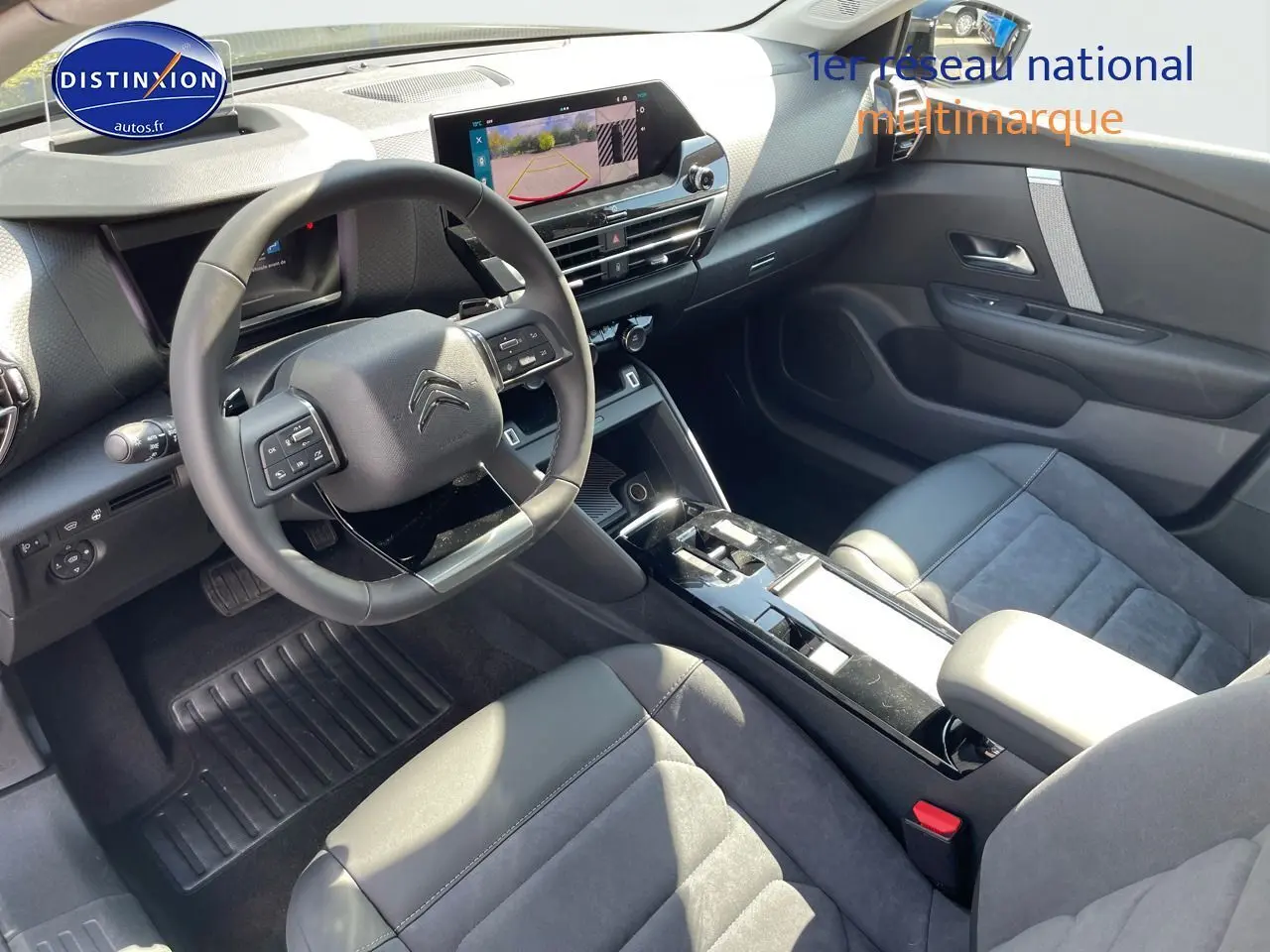 Intérieur du Citroën C4 2024 en gris, vue côté conducteur montrant volant, écran tactile et sièges cuir noir.