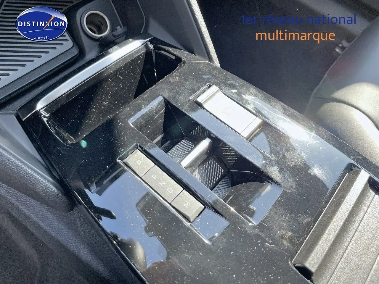 Gros plan sur la console centrale noire brillante de la Citroën C4 2024 avec commandes de boîte automatique et rangement.