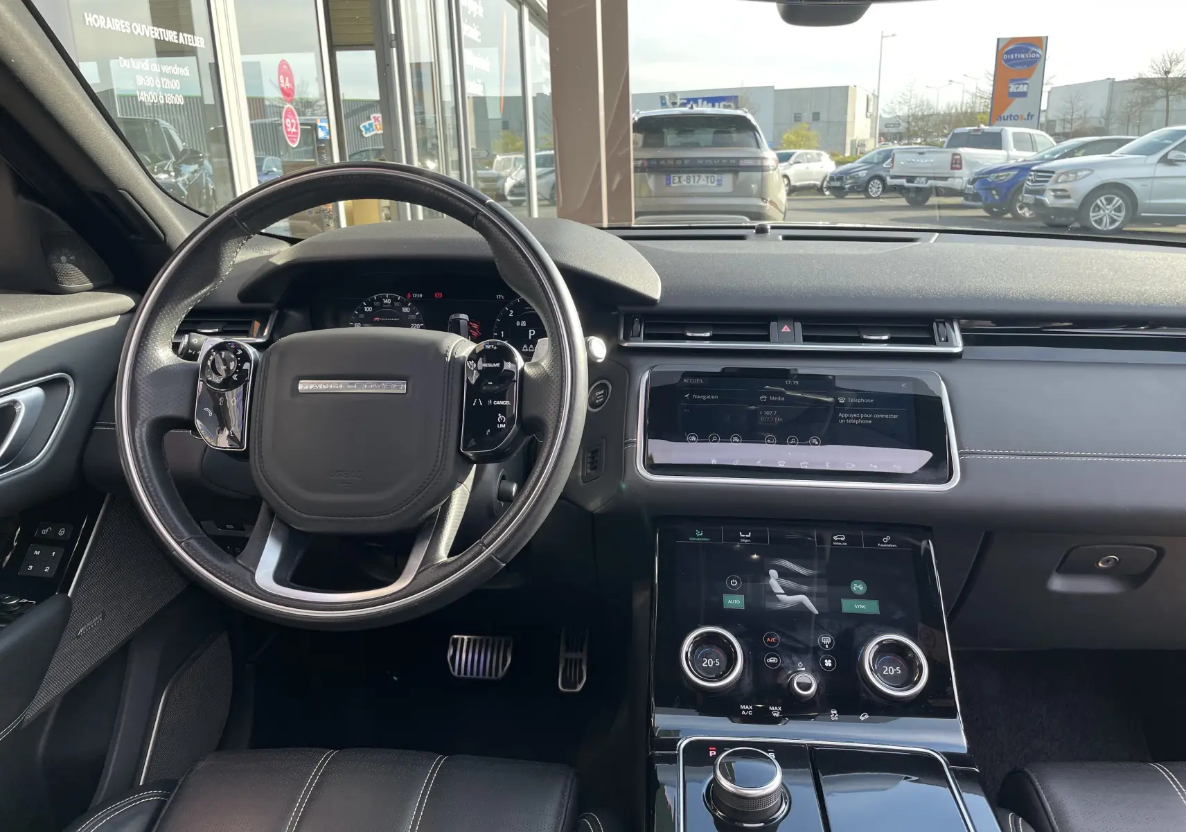Vue intérieure du tableau de bord et volant du Range Rover Velar noir Santorini, avec écran tactile et finitions cuir noires.