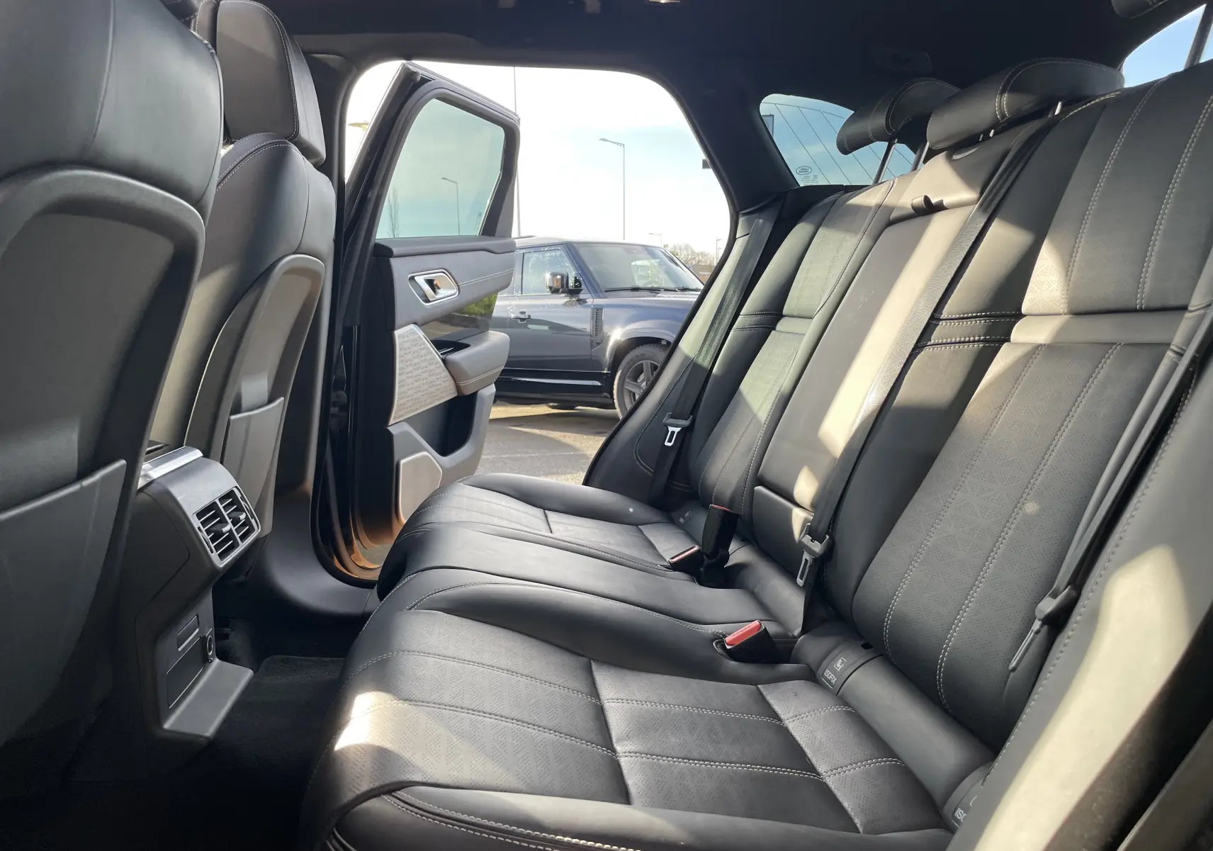Vue intérieure du Range Rover Velar noir Santorini montrant la banquette arrière en cuir avec porte arrière gauche ouverte.