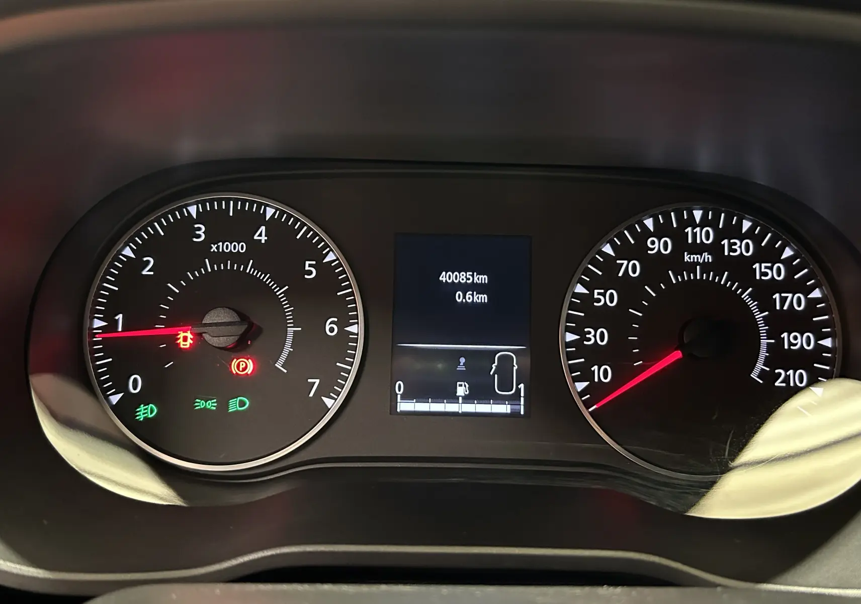 Vue rapprochée du tableau de bord du Dacia Duster orange Arizona 2022, affichant le compteur et les voyants allumés.