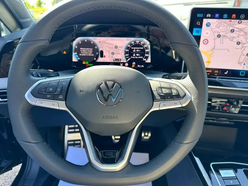 Vue rapprochée du volant noir de la Volkswagen Golf 1.5 eTSI R-Line 2025 avec tableau de bord digital et écran tactile.