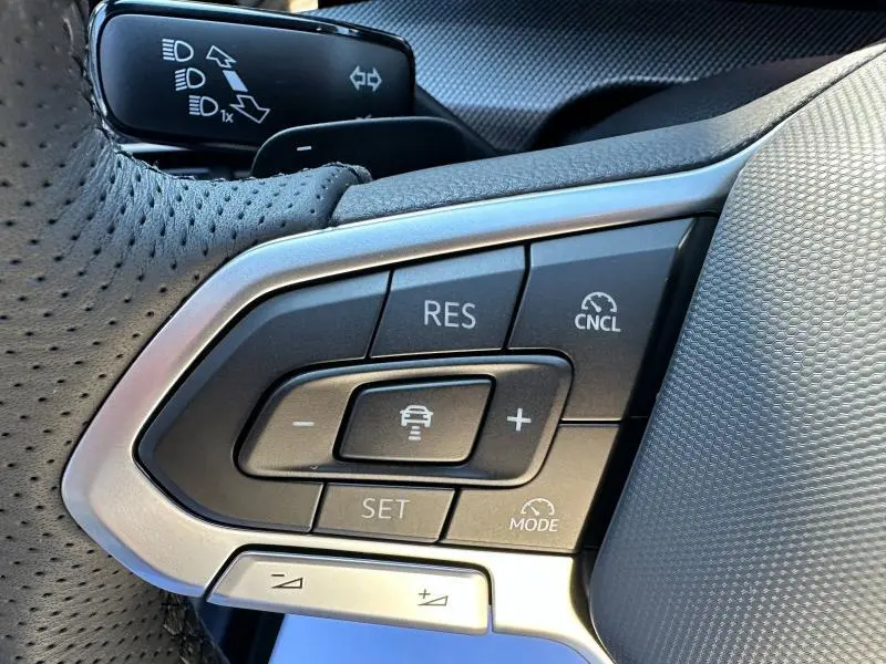 Gros plan sur les commandes du régulateur de vitesse au volant perforé d'une Volkswagen Golf noire 2025 R-Line Edition.