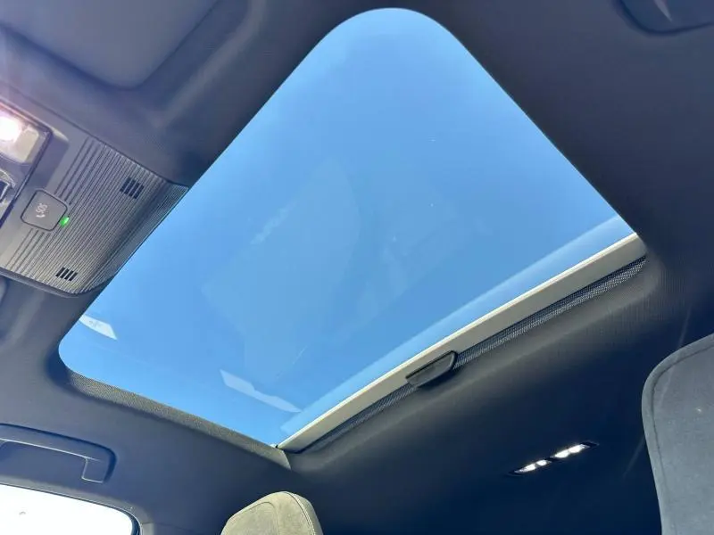 Toit panoramique ouvert vu de l'intérieur d'une Volkswagen Golf 2025 noire, avec ciel bleu visible à travers le vitrage.