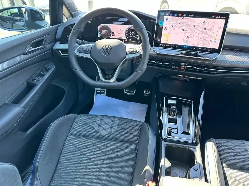 Vue intérieure avant de la Volkswagen Golf 1.5 eTSI R-Line 2025 noire, avec tableau de bord numérique et écran tactile central.