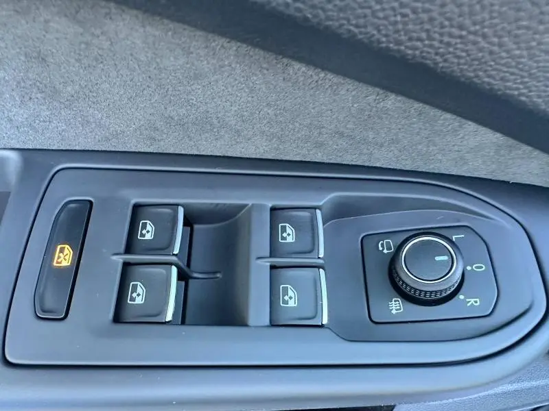 Gros plan sur les commandes de lève-vitres et réglage des rétroviseurs d’une Volkswagen Golf noire 2025 R-Line Edition.