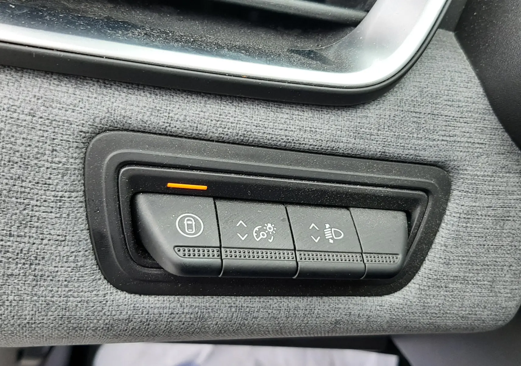 Gros plan sur les commandes de réglage des phares et du tableau de bord dans une Renault Clio V gris schiste, côté conducteur.