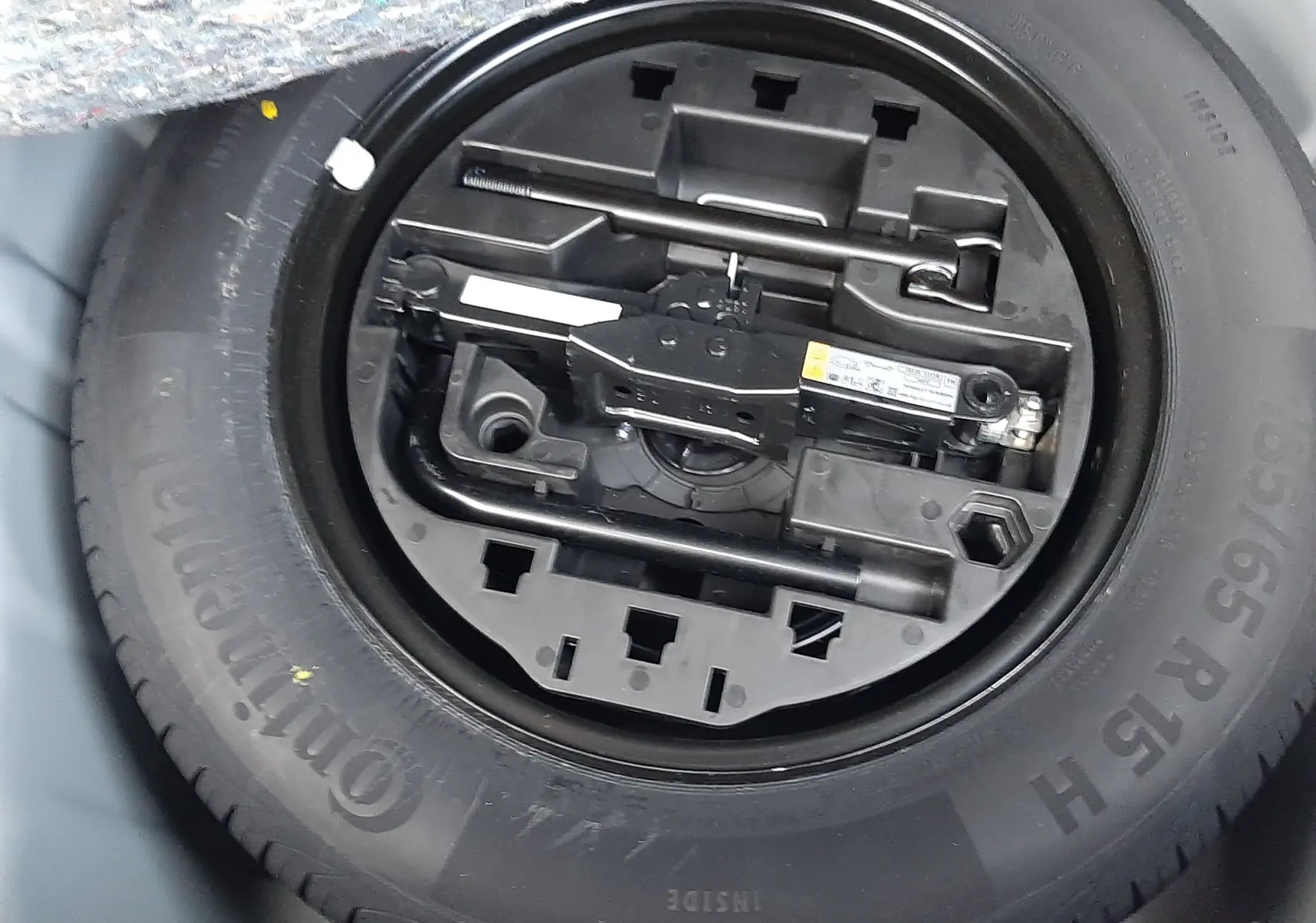 Gros plan sur la roue de secours et les outils de bord dans le coffre d'une Renault Clio V gris schiste hybride 2024.