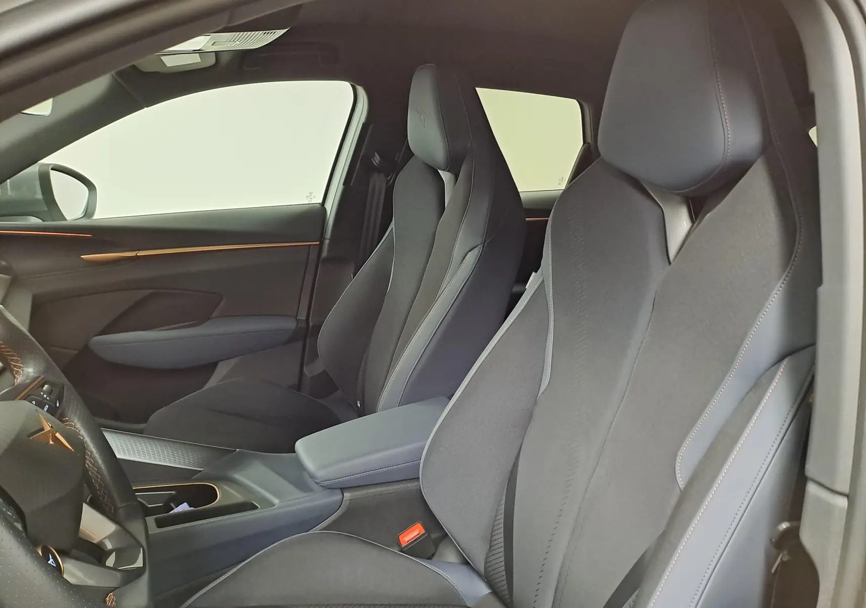Intérieur de la CUPRA TERRAMAR 2025 vu côté droit, sièges sport noirs avec surpiqûres orange et détails modernes.