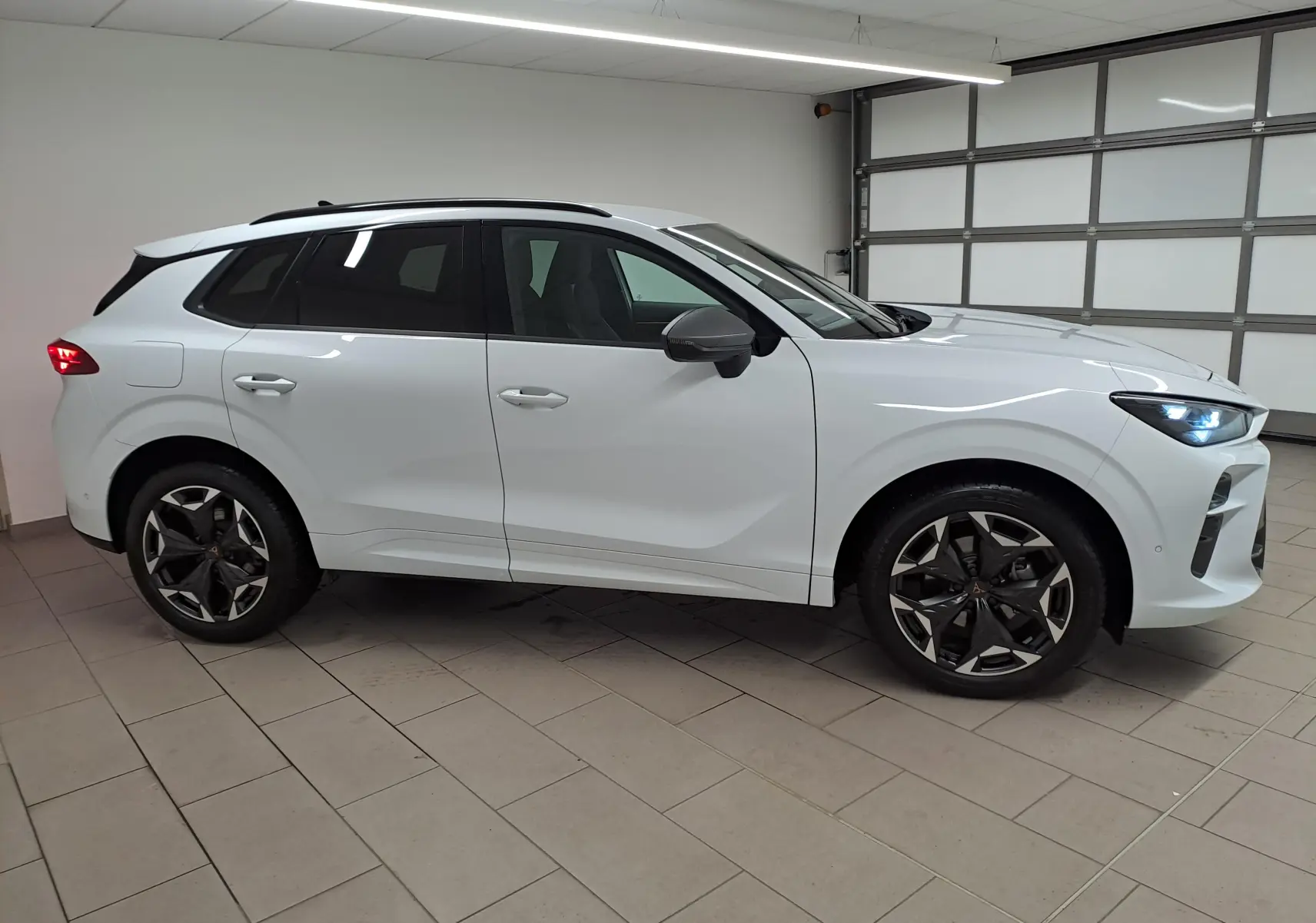 Vue de profil droit du CUPRA TERRAMAR blanc Nevada avec jantes 19'' Cosmic usinées dans un garage.