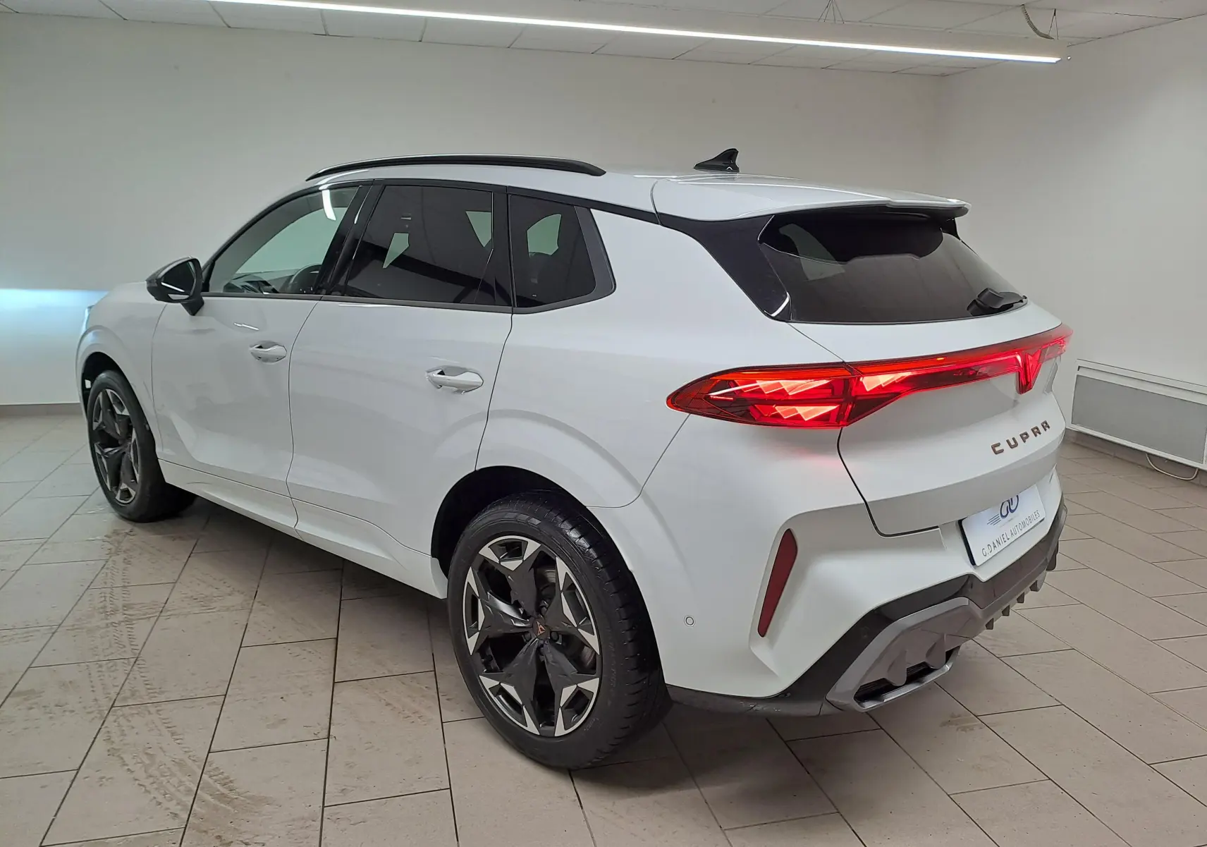 Vue 3/4 arrière droite du CUPRA TERRAMAR blanc Nevada avec jantes 19'' Cosmic usinées et feux arrière allumés.