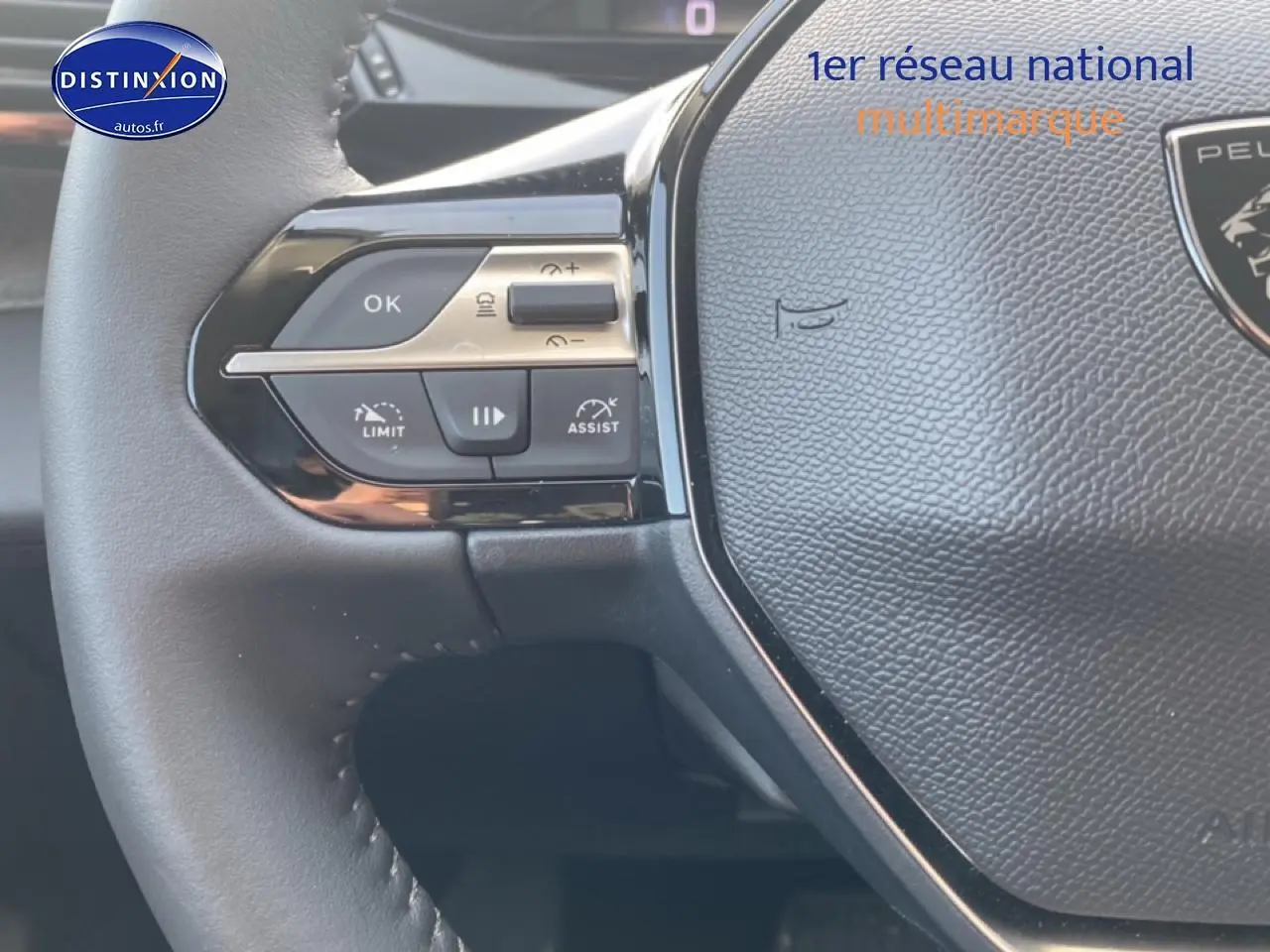 Gros plan sur le volant noir de la Peugeot 308 SW gris sellenium, avec commandes multifonctions visibles à gauche.