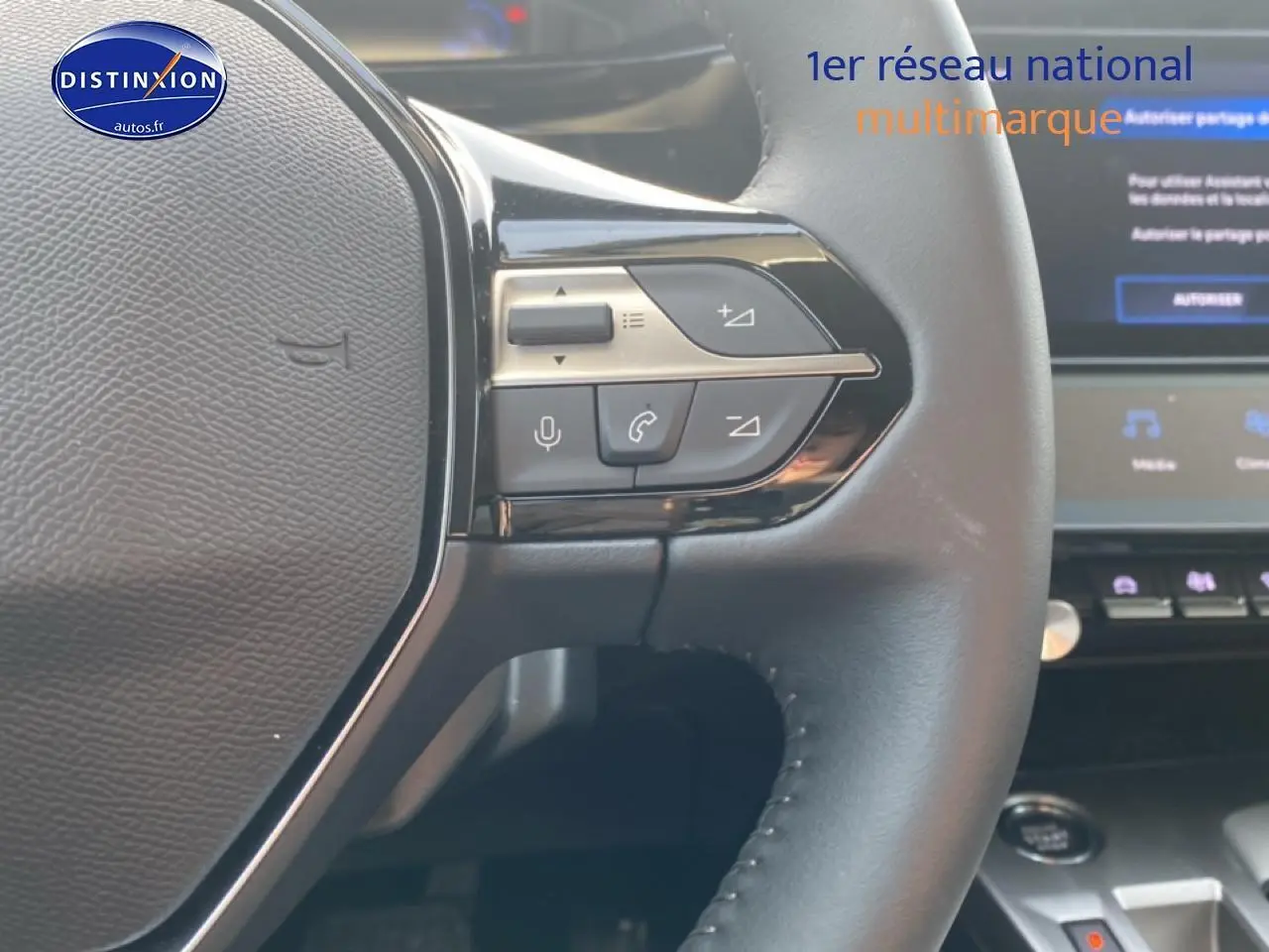 Gros plan sur le volant multifonction noir de la Peugeot 308 SW 1.2 hybrid 145 allure e-dcs6 avec commandes audio intégrées.