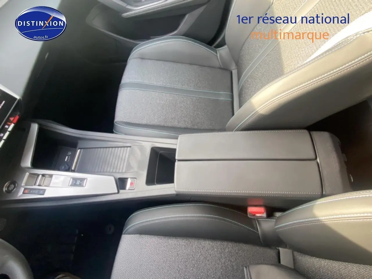 Vue intérieure en plongée du tunnel central et accoudoir noir du Peugeot 308 SW gris sellenium, avec console moderne et sièges tissu.