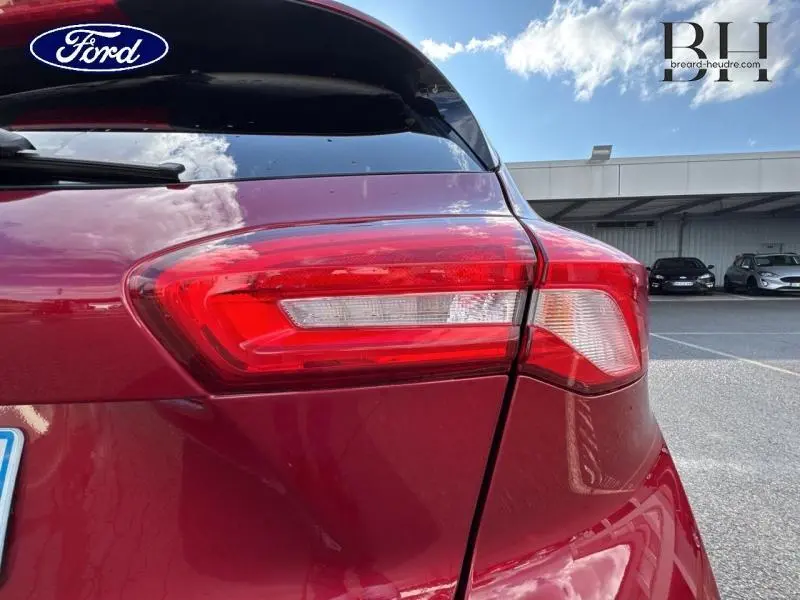 Gros plan sur le feu arrière droit d'une Ford Focus 1.0 EcoBoost 125ch rouge Premium Candy, avec reflet du ciel.