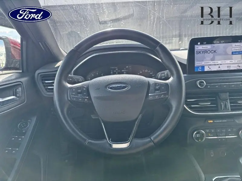 Vue intérieure centrée sur le volant cuir multifonction d'une Ford Focus 1.0 EcoBoost avec écran tactile et tableau de bord numérique.