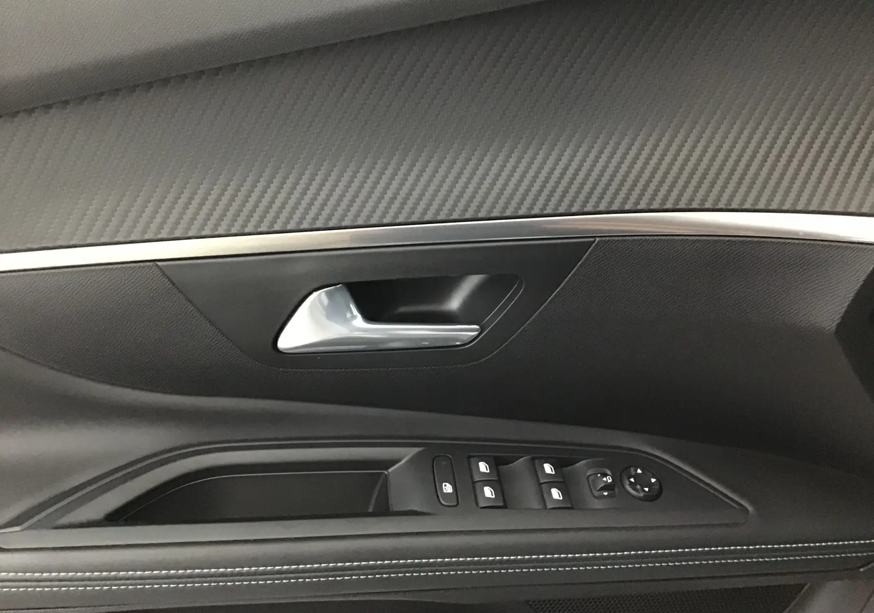 Gros plan sur la garniture intérieure de la porte côté gauche du Peugeot 5008 blanc nacré, avec commandes des vitres et poignée argentée.