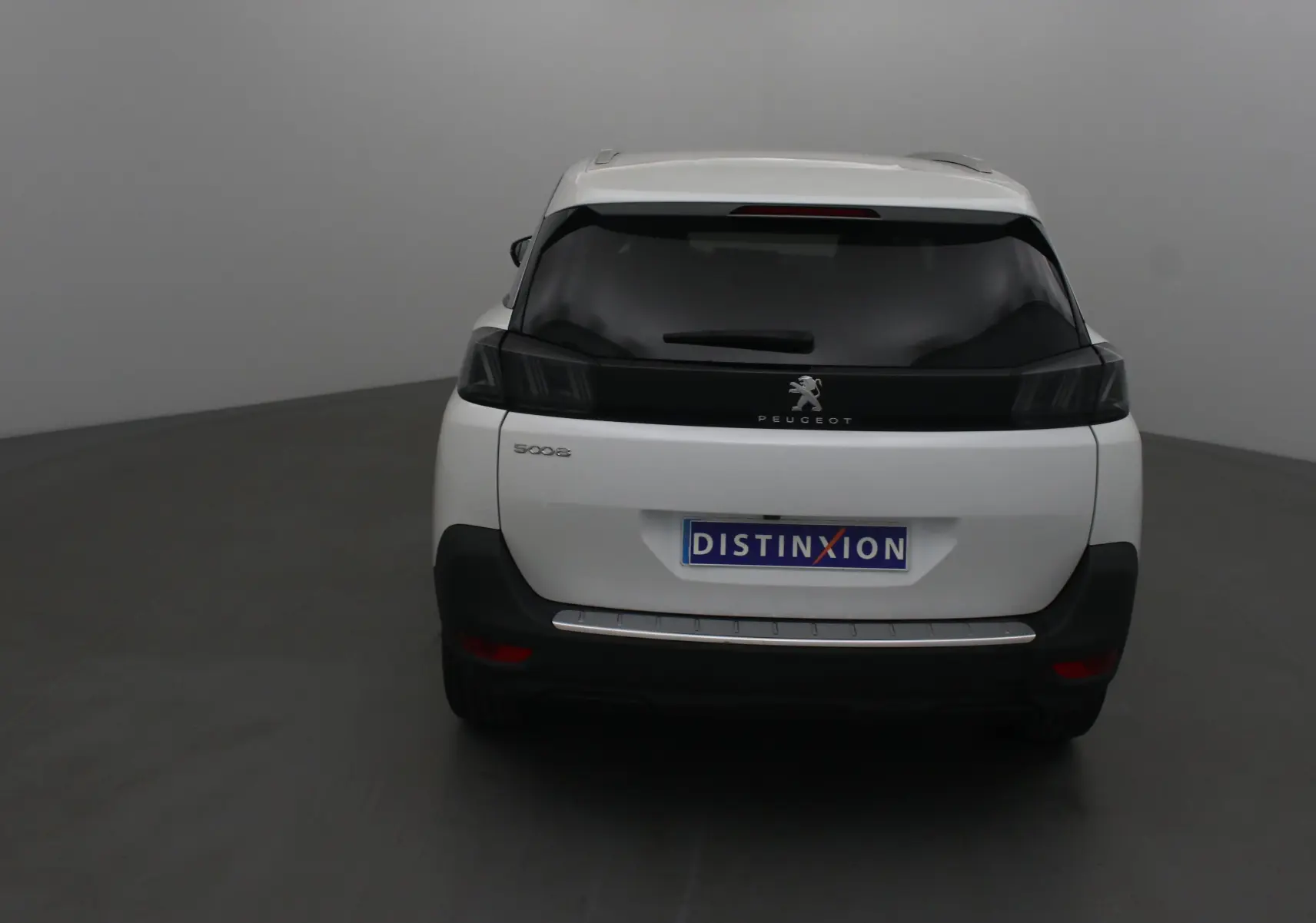 Vue arrière d'un Peugeot 5008 blanc nacré avec vitres teintées et logo Peugeot visible sur le hayon.