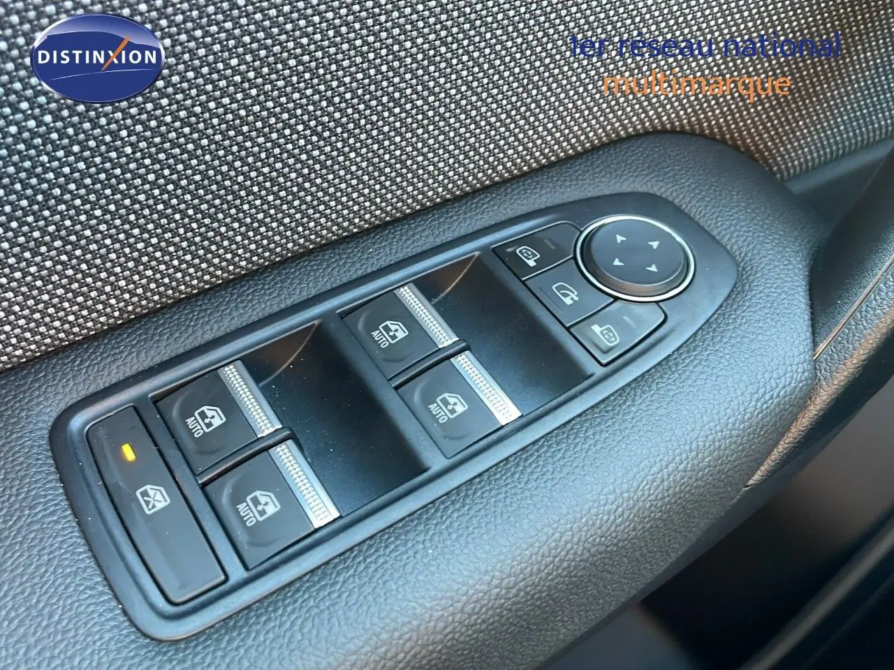 Gros plan sur les commandes des vitres électriques et réglages des rétroviseurs côté conducteur du Renault Captur blanc nacré.