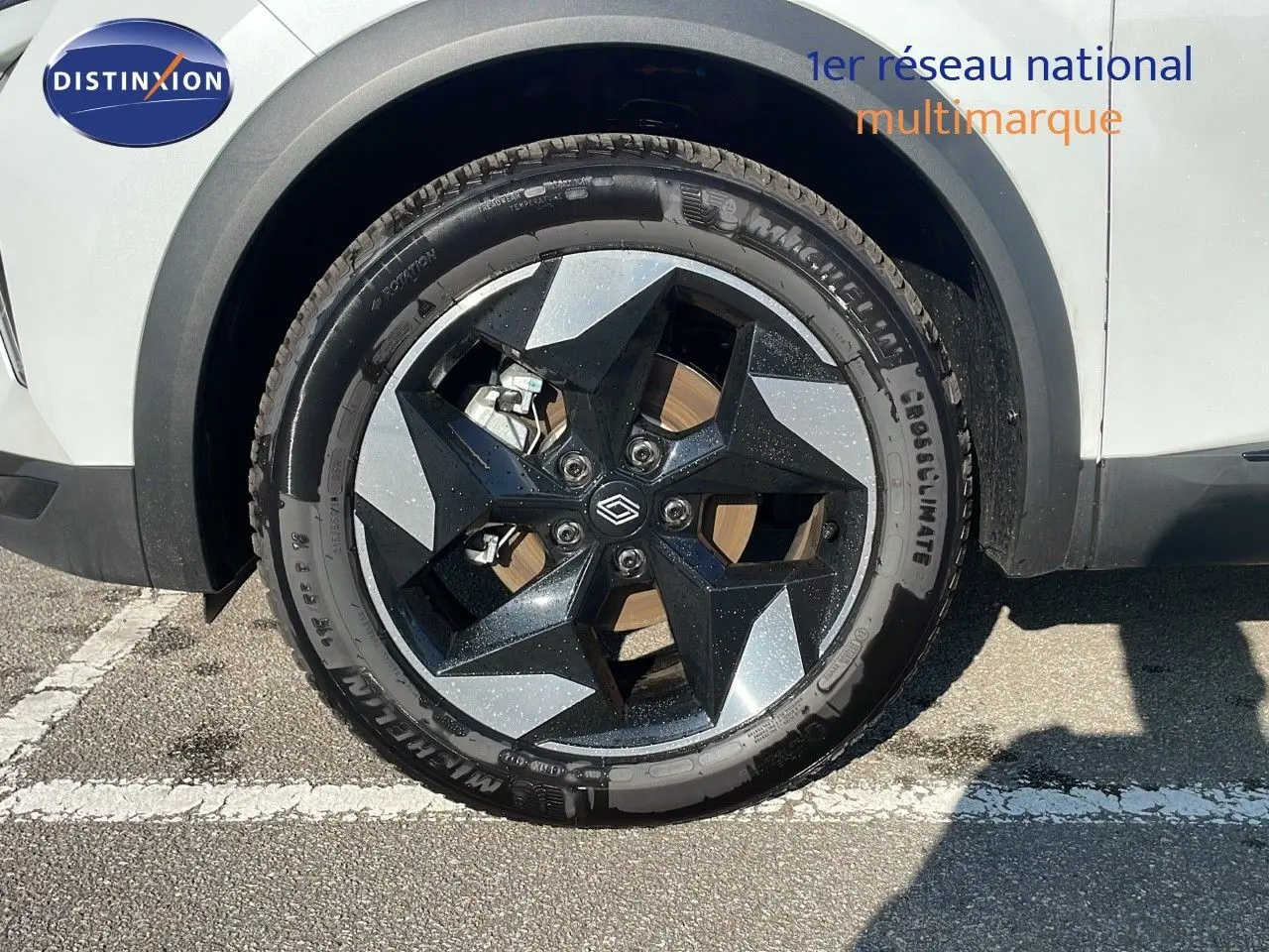 Gros plan sur la roue avant gauche du Renault Captur blanc nacré avec jante noire et grise au design géométrique.