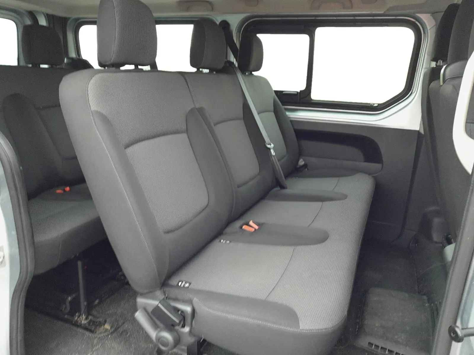 Vue intérieure latérale droite des sièges arrière gris foncé du Renault Trafic Combi L2 2023, montrant trois places avec appuie-têtes.