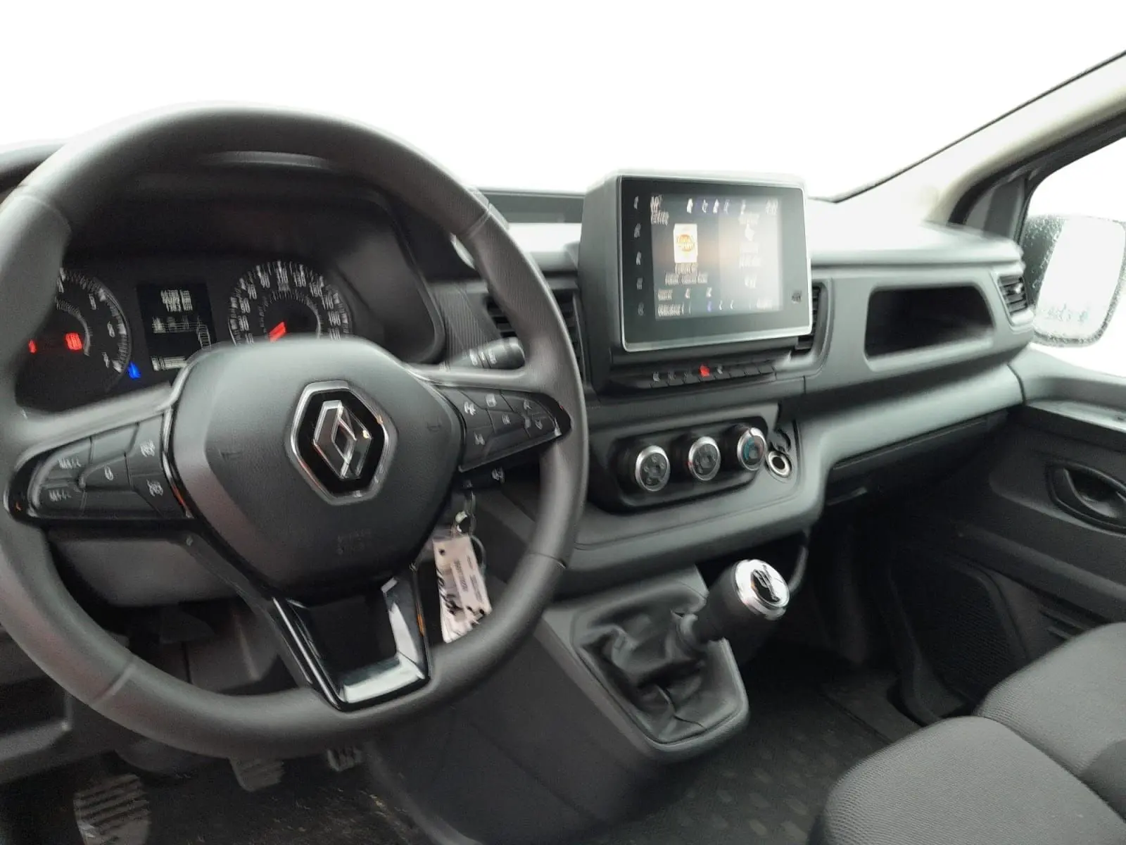 Intérieur du Renault Trafic Combi 2023, vue du poste de conduite avec volant multifonction et écran tactile central.