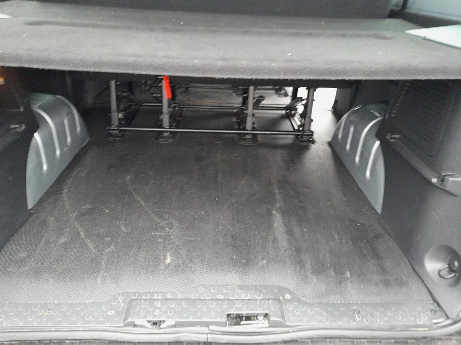 Espace de chargement vu de l'arrière du Renault Trafic Combi gris clair, avec plancher caoutchouté et structure métallique sous les sièges.