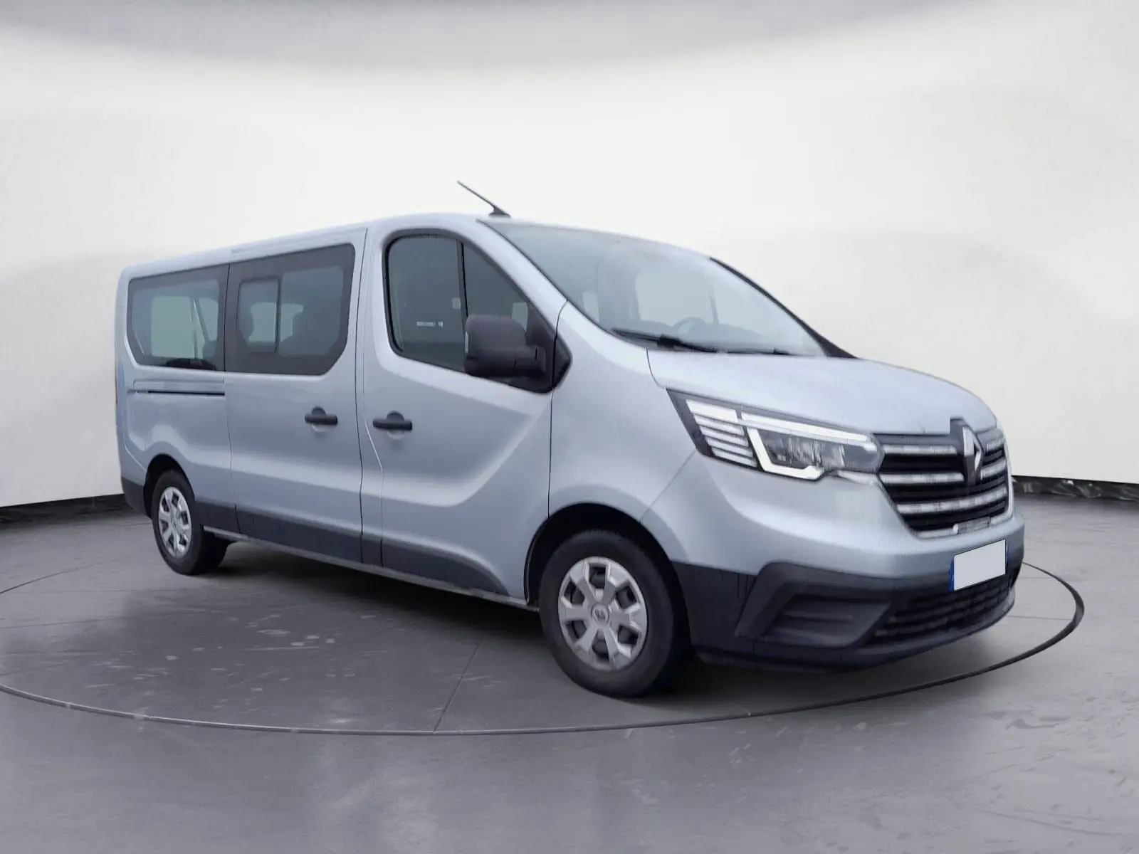 Renault Trafic Combi gris clair métal vu de trois quarts avant droit, mettant en valeur ses grandes fenêtres latérales.