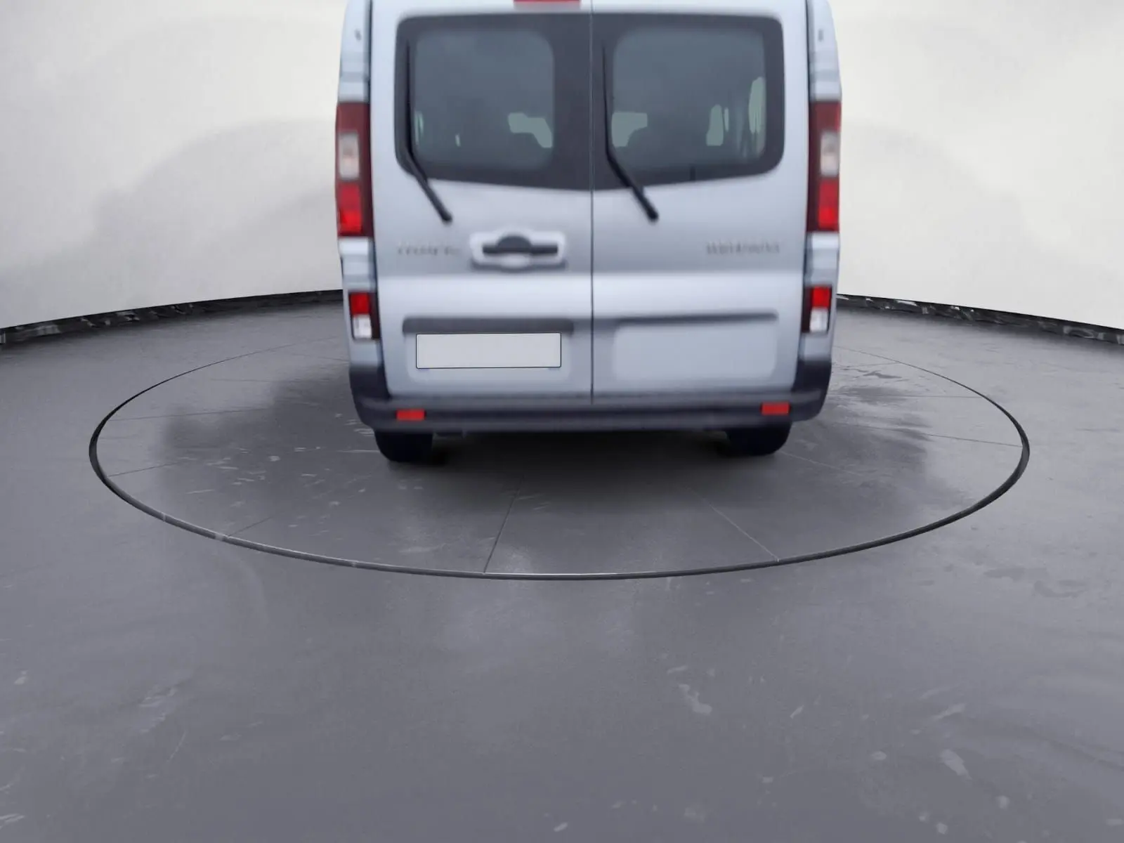 Vue arrière d'un Renault Trafic Combi gris clair métal 2023, avec portes battantes et essuie-glaces arrière visibles.
