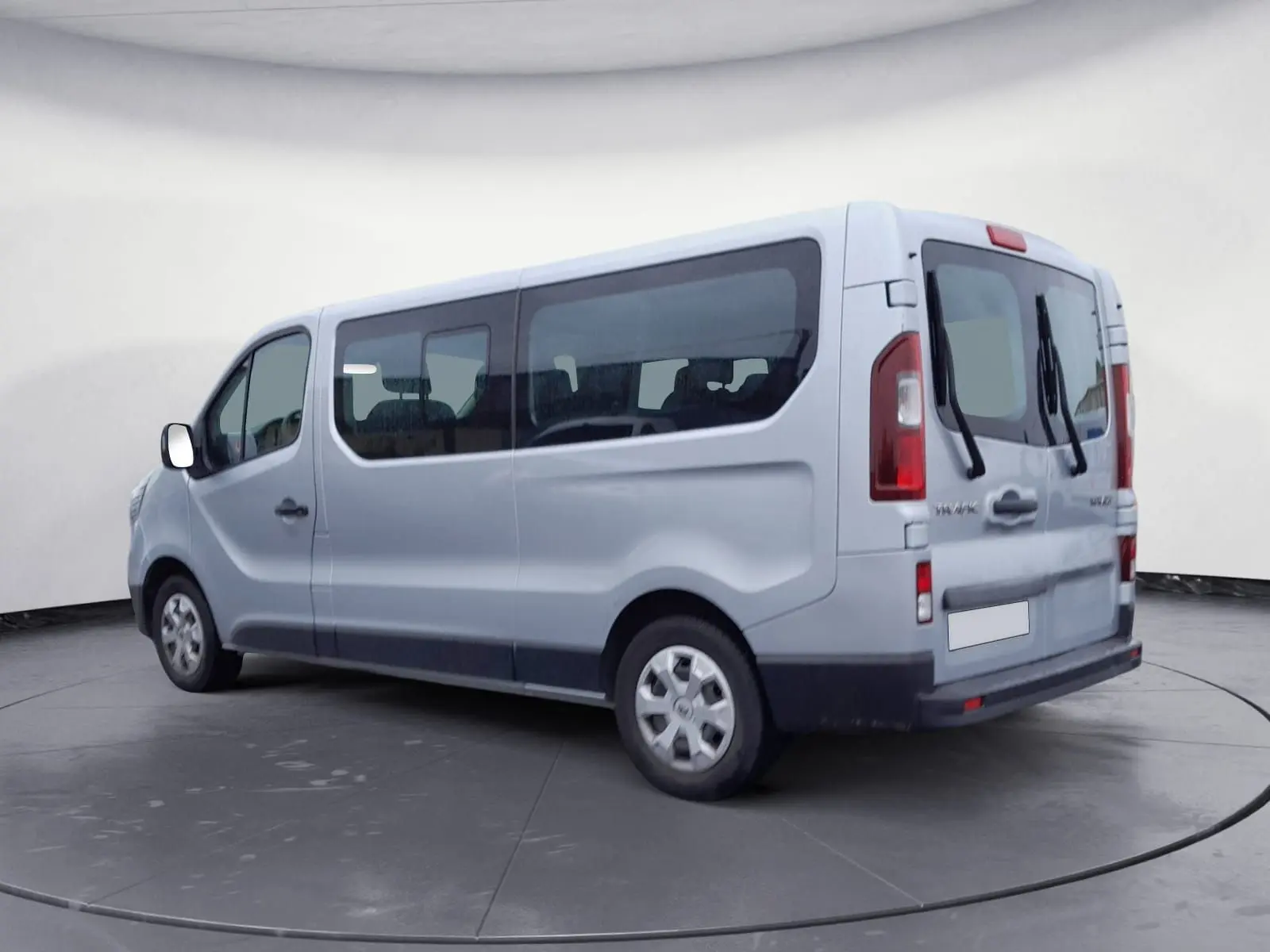 Vue 3/4 arrière droit du Renault Trafic Combi gris clair métal, grand van avec vitres latérales teintées et portes arrière battantes.