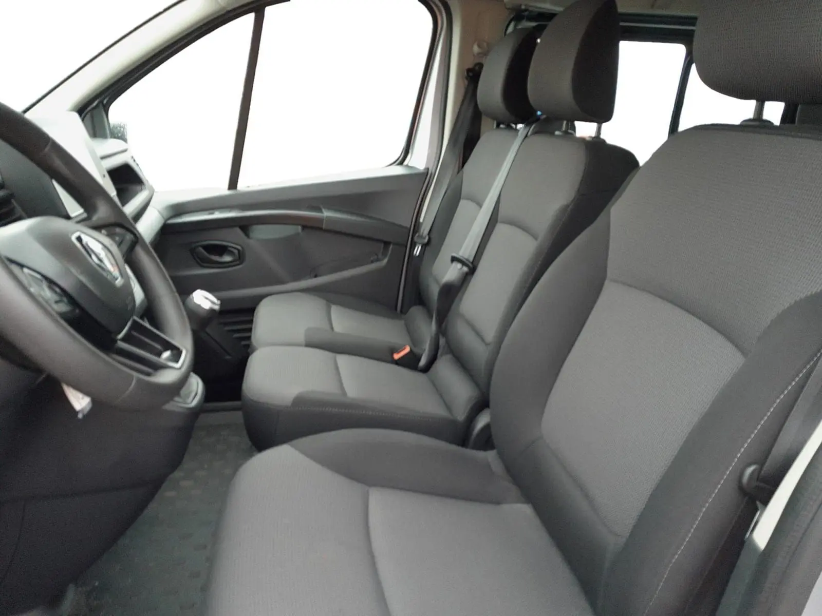 Vue intérieure côté conducteur du Renault Trafic Combi 2023, sièges gris foncé en tissu et volant multifonction.