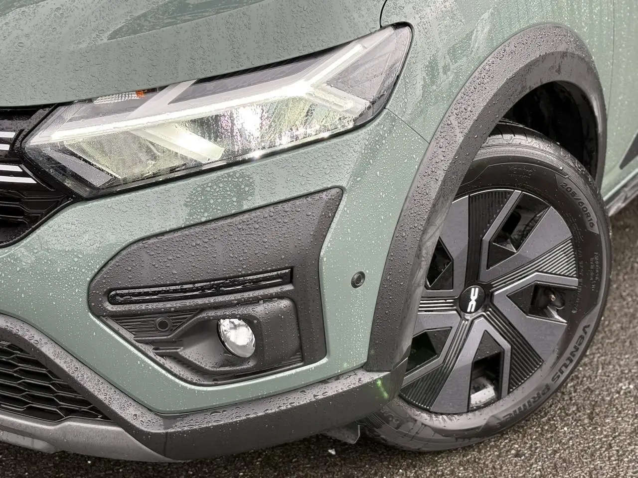Gros plan sur l'avant droit du Dacia Jogger Kaki Lichen, mettant en valeur le phare LED et la roue avec enjoliveur noir.