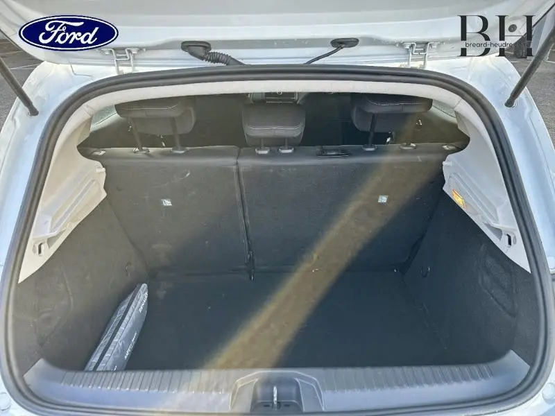 Vue du coffre ouvert d'une Renault Clio blanche 2020, montrant l'espace de chargement avec banquette arrière en tissu noir.