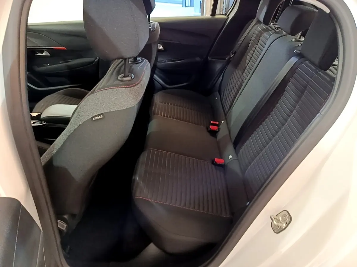 Vue intérieure côté arrière droit de la banquette noire avec surpiqûres rouges de la Peugeot 208 Electrique Active Business blanche.