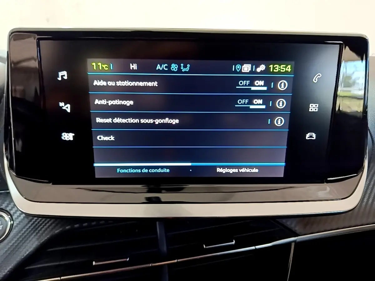 Écran tactile central affichant les réglages d'aide à la conduite dans une Peugeot 208 électrique blanche, vue intérieure.