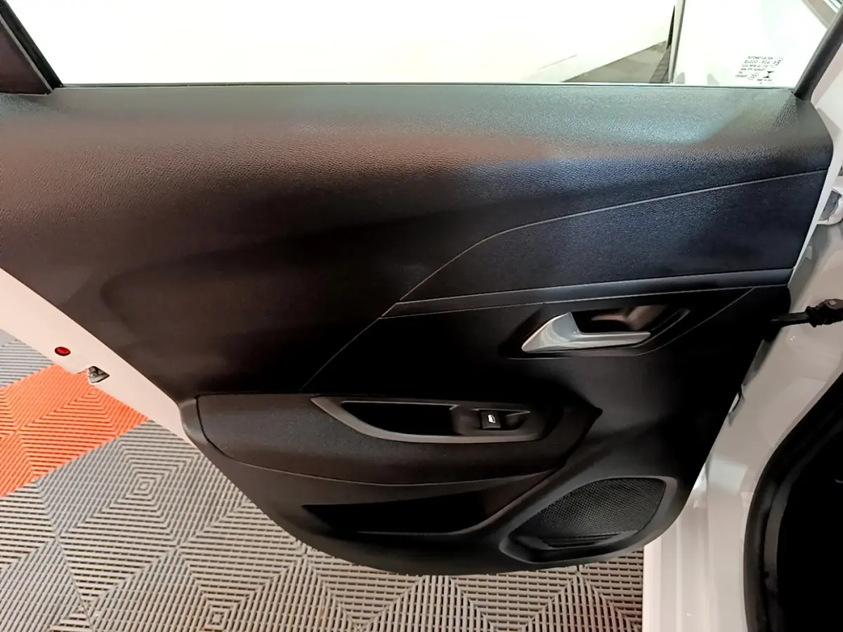 Vue intérieure côté gauche de la porte arrière noire d’une Peugeot 208 Electrique Active Business blanche.