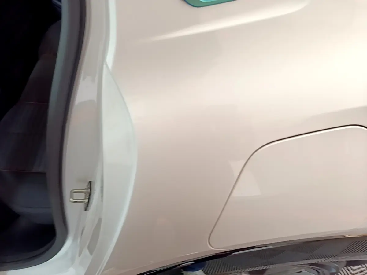 Vue rapprochée côté gauche arrière d’une Peugeot 208 électrique blanche, avec trappe de recharge visible.