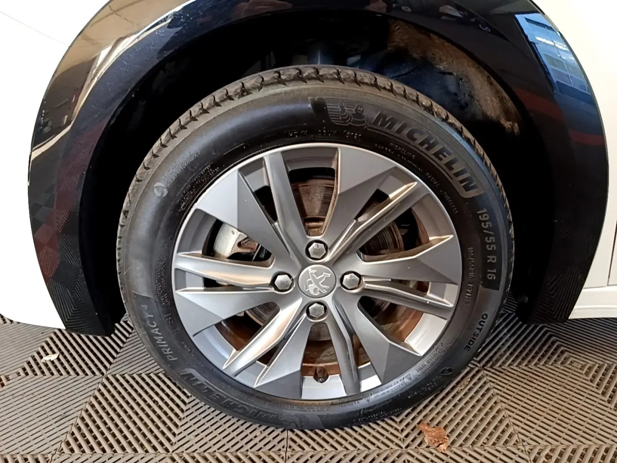 Gros plan sur la roue avant droite avec jante alliage grise et pneu Michelin d'une Peugeot 208 blanche.